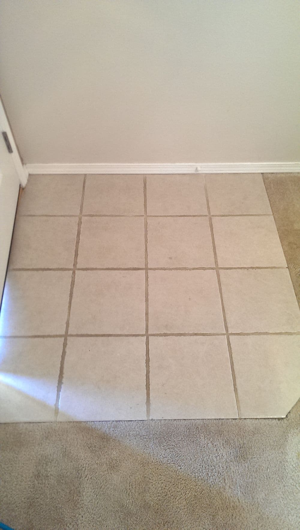 Tile flooring transition from carpet to tiles, featuring a light-colored pattern and clean lines.